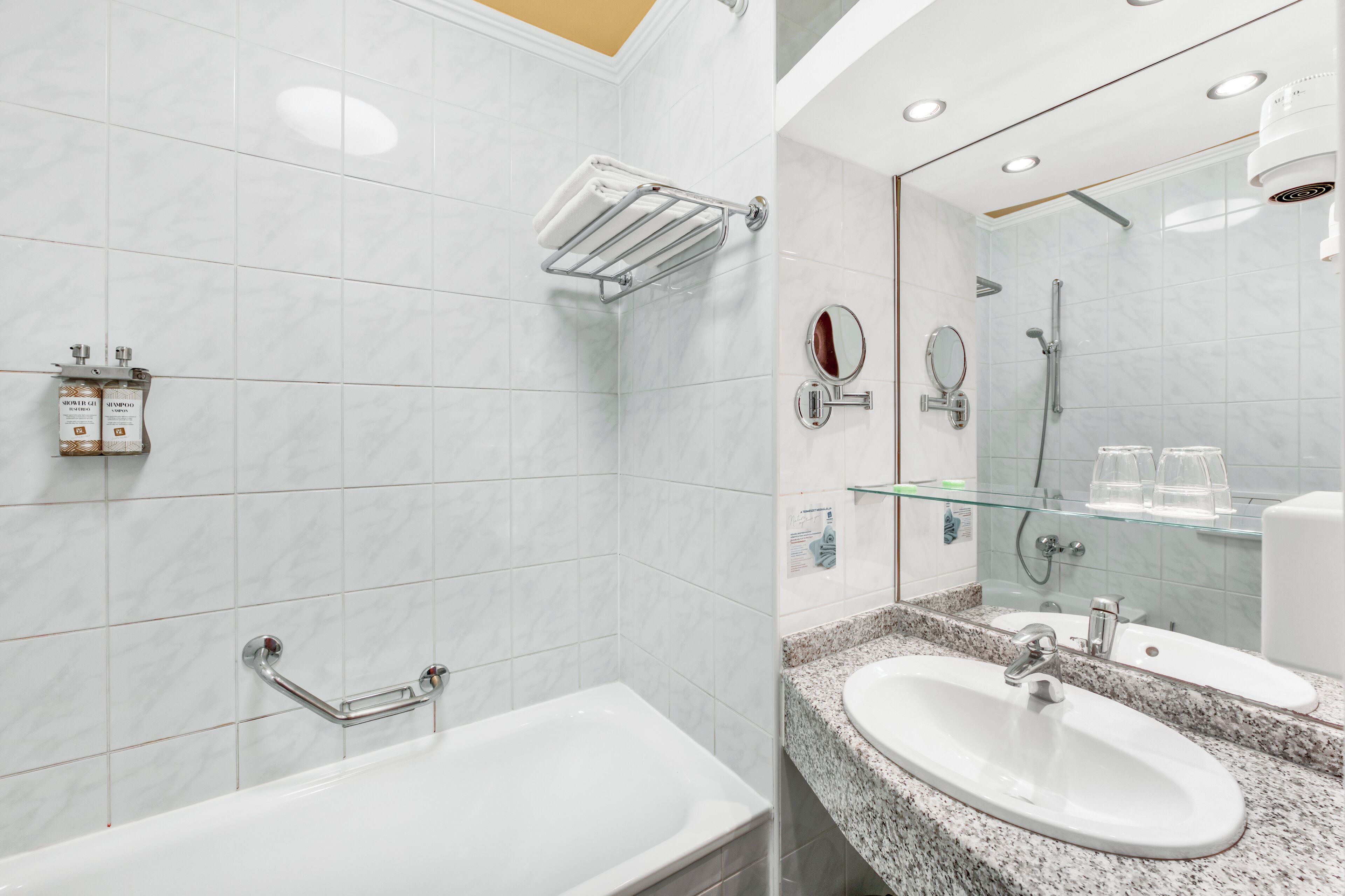 Ein modernes Badezimmer mit Badewanne, Waschtisch und Duschkabine aus Glas, sowie einem Spiegel.