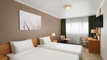 Habitación de hotel con dos camas, un escritorio, una silla, un televisor y un cuadro en la pared.