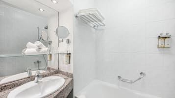 A modern bathroom with a granite countertop sink, a glass-enclosed mirror, a handheld showerhead, and a white bathtub with a chrome grab bar.