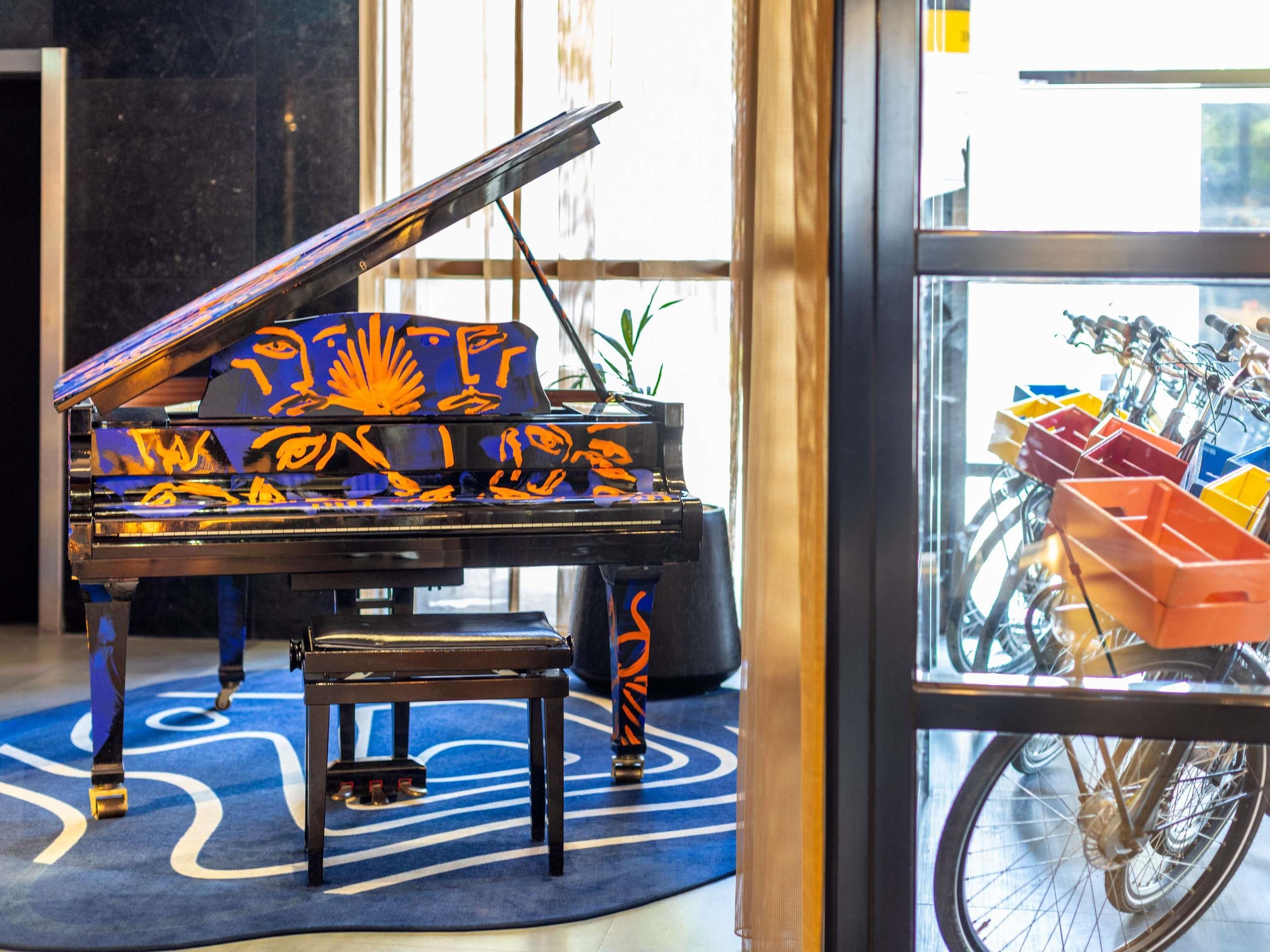 Un piano de cola imponente con un diseño único, un aparcamiento para bicicletas en el exterior y una alfombra azul estampada.