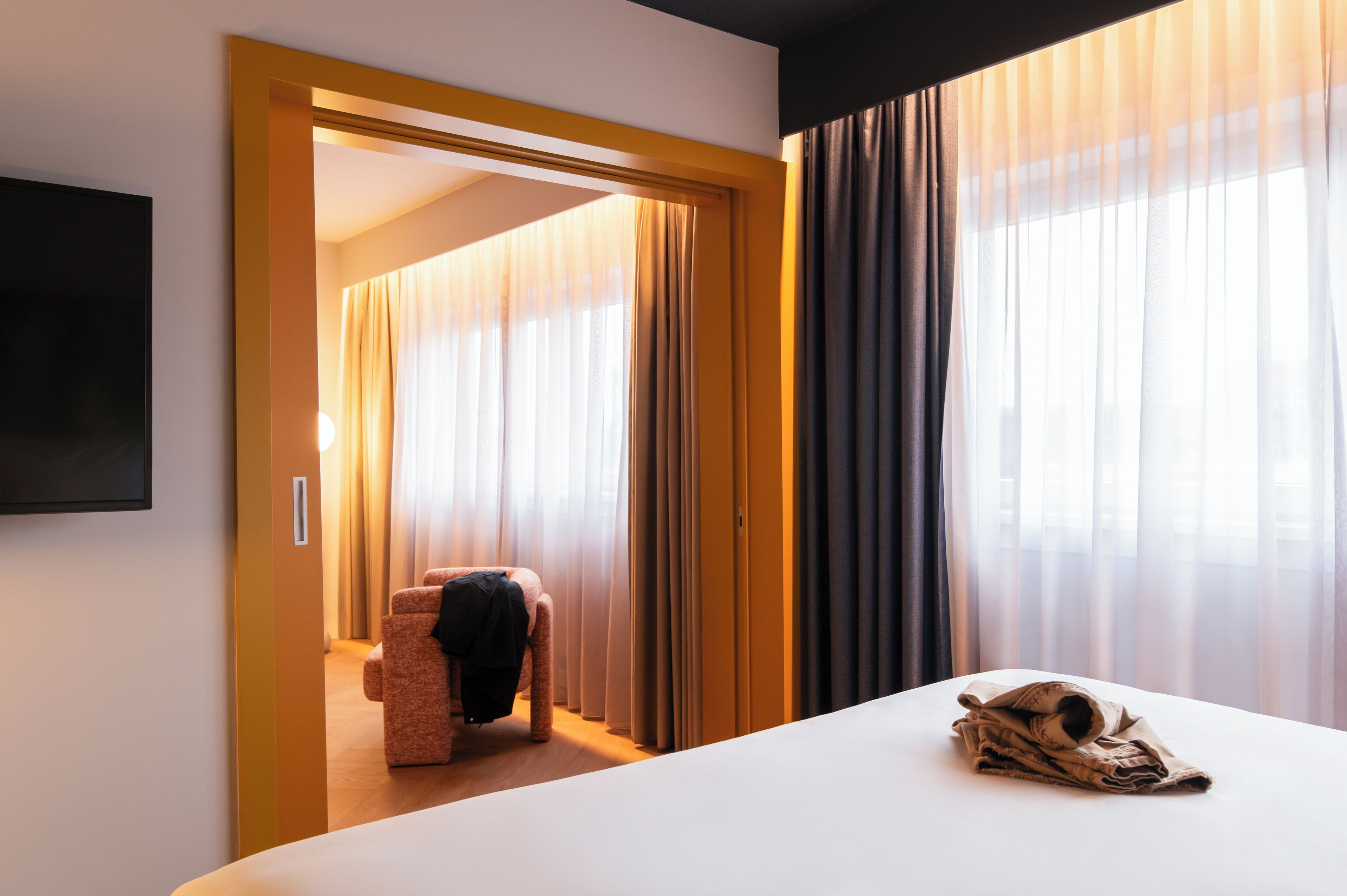 Ein Hotelzimmer mit einem Bett, einem Sessel und einem an der Wand befestigten Fernseher.