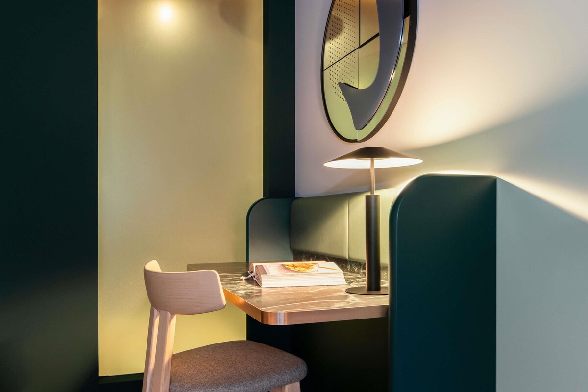 Un bureau d’angle avec une chaise, une lampe et un livre dessus.