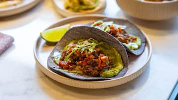 A plate of tacos with a lime wedge on a table.