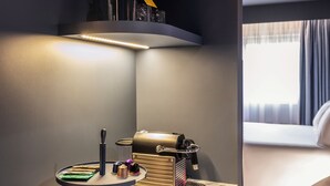 Een moderne hotelkamer met een marmeren aanrechtblad, een koffieapparaat, een waterkoker en een fles water.