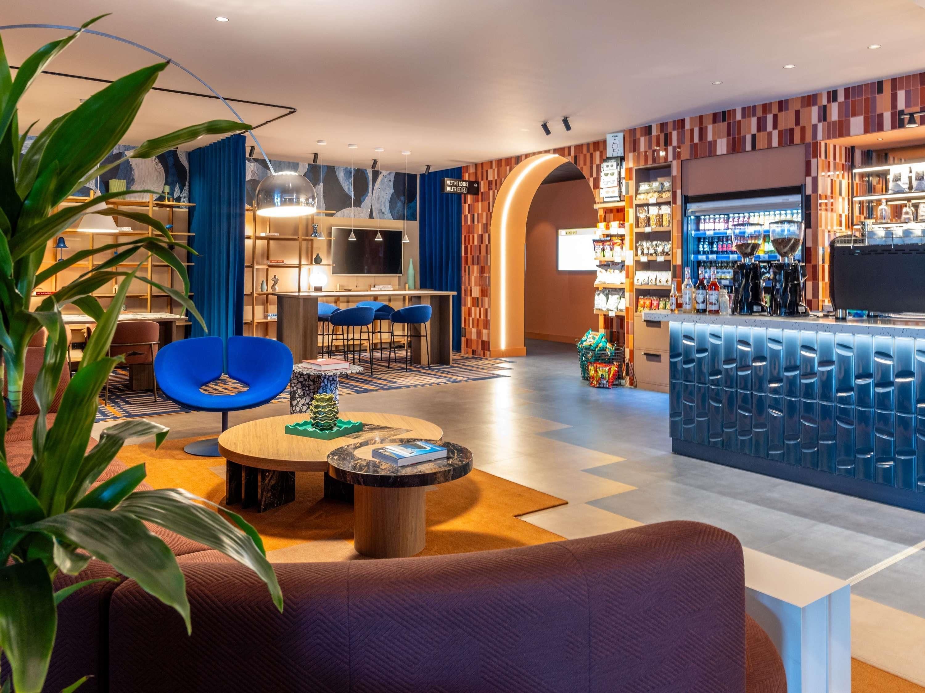 Un moderno vestíbulo de hotel con un bar, zona de estar y televisor.