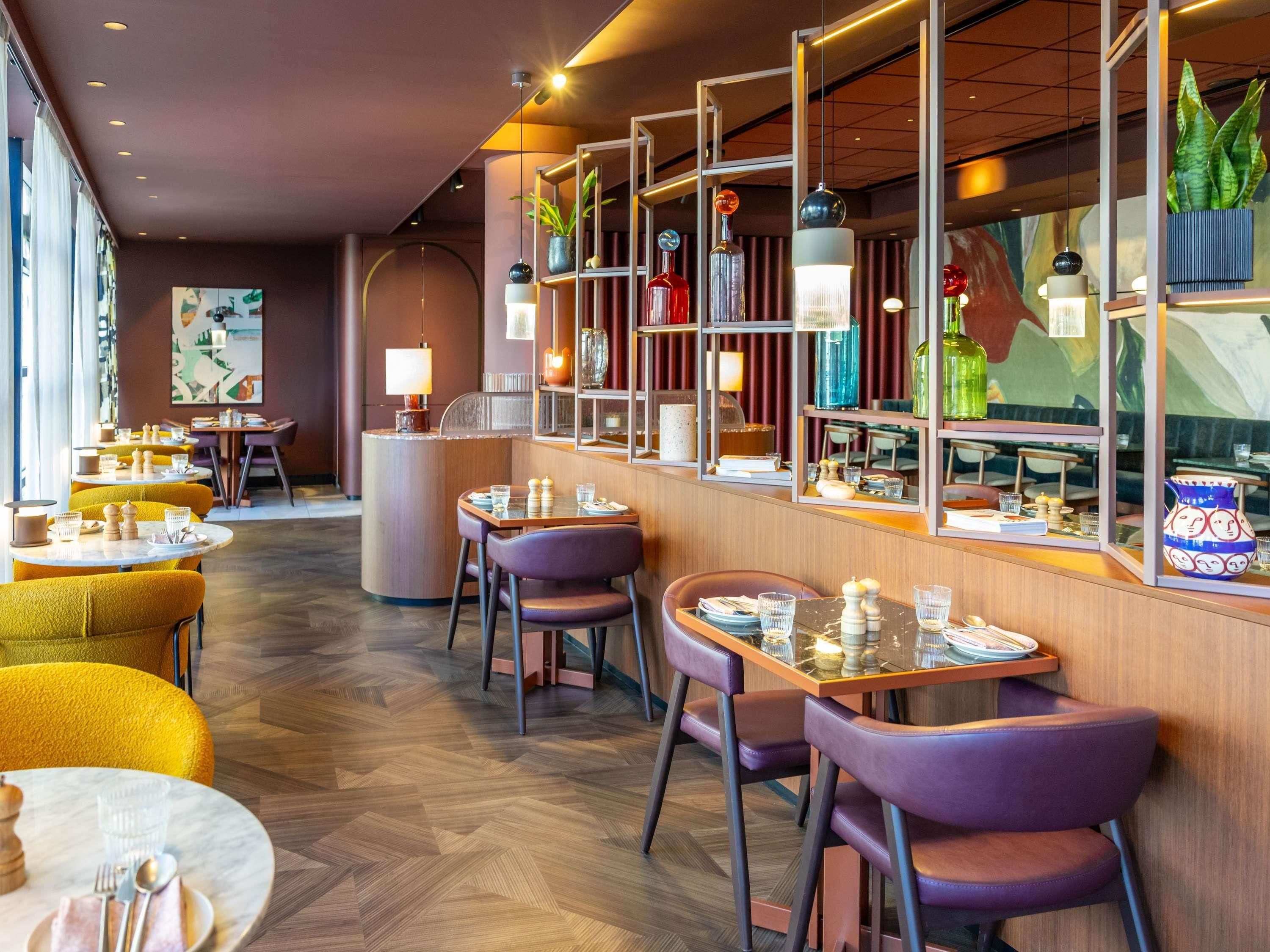 A restaurant with round tables, purple chairs, and a herringbone wood floor.