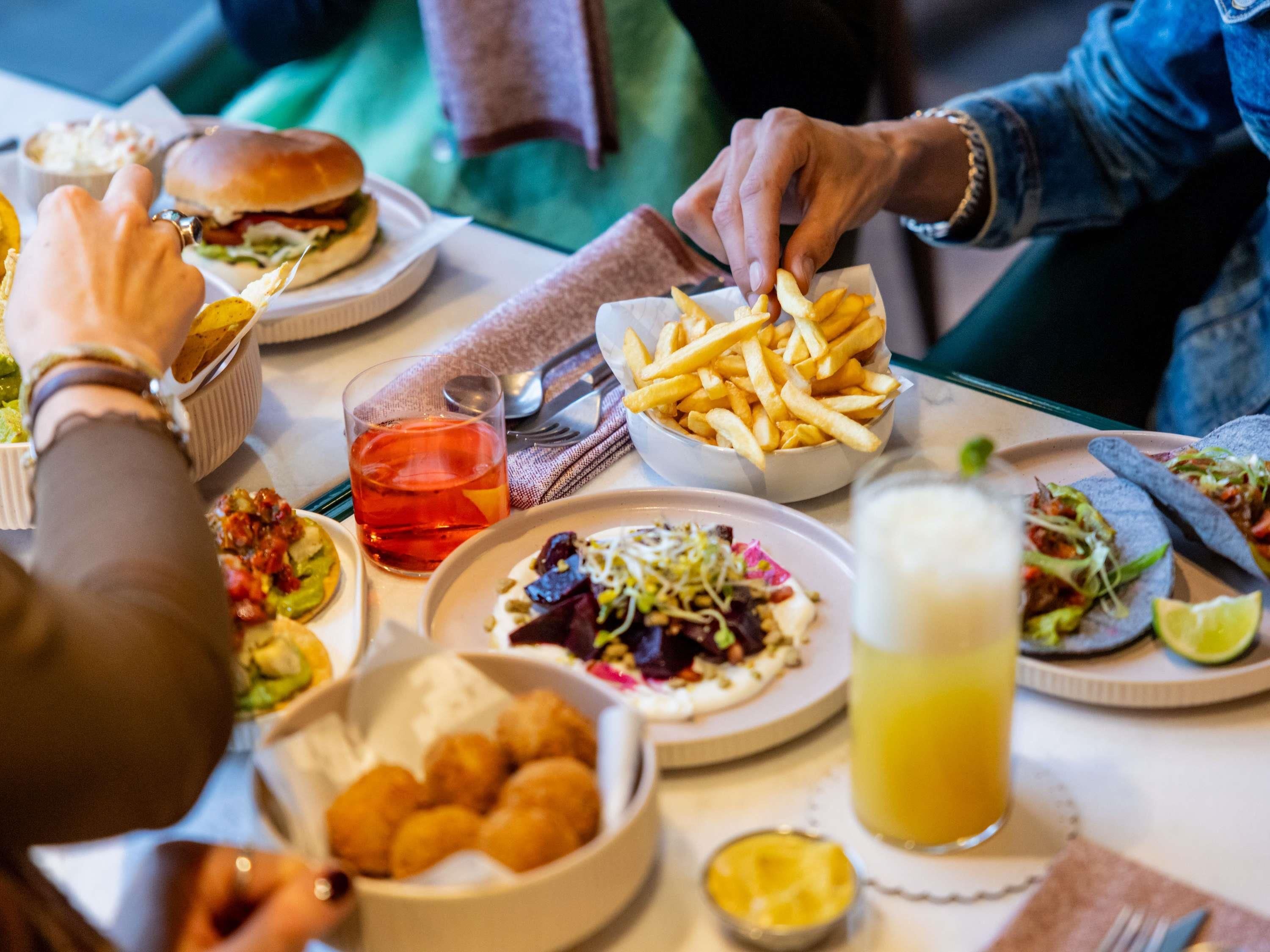A dining table with various dishes, a glass of red drink, and a glass of yellow beverage.
