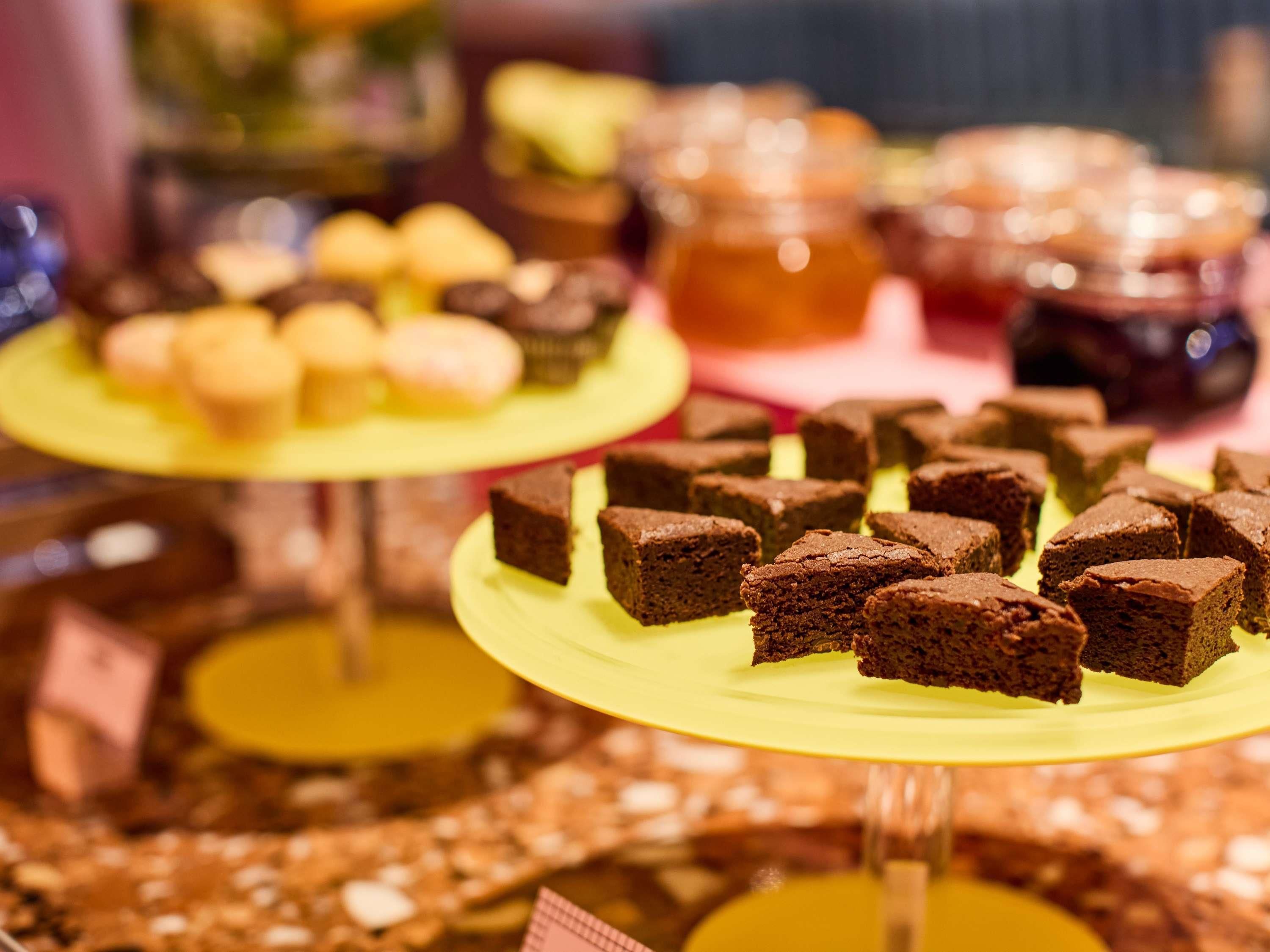 A dessert display with various baked goods on yellow stands.