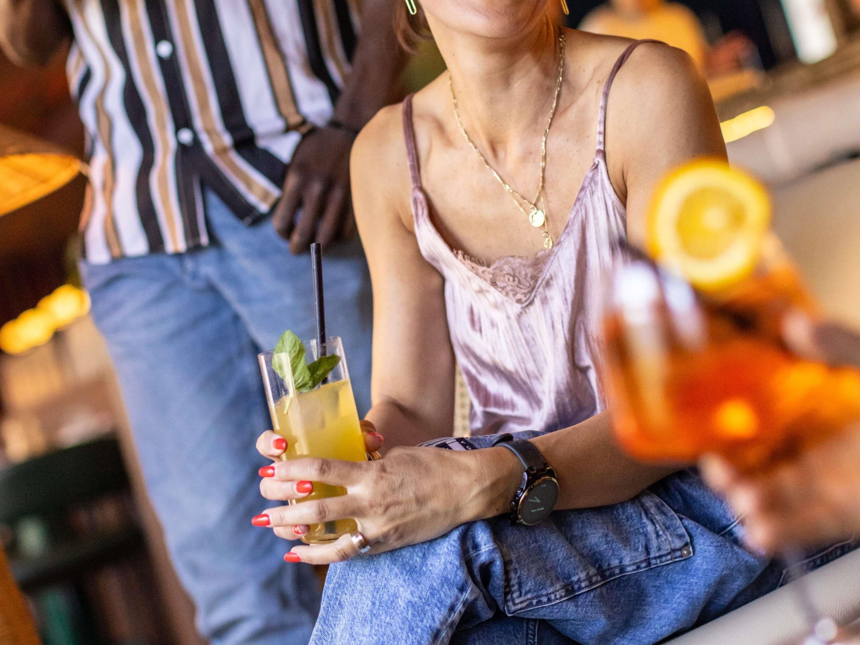 A person holding a drink with a straw and a slice of lemon.