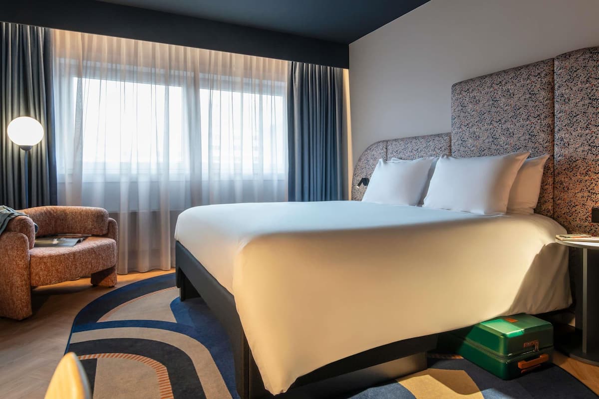 Une chambre d’hôtel avec un grand lit, une chaise, un bureau et une valise.