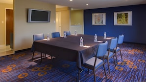 A conference room with a long table, chairs, water bottles, and a flat-screen TV on the wall. - Heritage Place Houston Brookhollow (Houston)