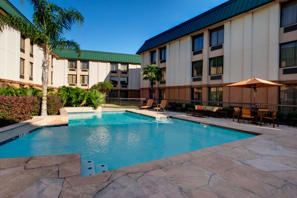 A hotel pool area with a clear blue pool, lounge chairs, and a covered seating area. - Heritage Place Houston Brookhollow (Houston)