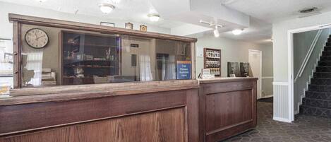 A reception desk with a clock, a sign for trail passes, and a staircase in the background.