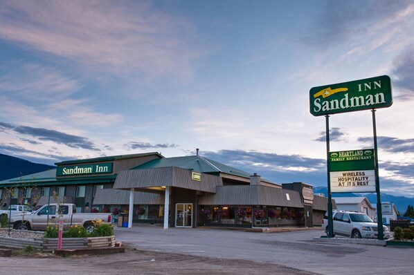 A Sandman Inn with a prominent sign, a parking lot, and a mountain backdrop.