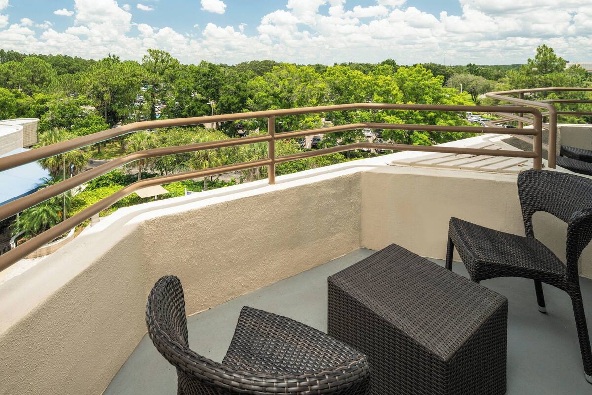 Un balcón con mobiliario de mimbre y vistas a un paisaje verde.