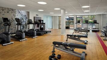 A gym with treadmills, elliptical machines, and weight benches.