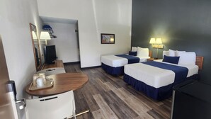 Een hotelkamer met twee bedden, een bureau, een stoel, een klein tafeltje, een spiegel en een wandlamp.