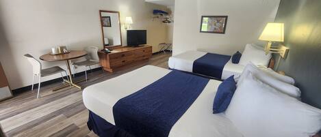 A hotel room with two beds, a desk with a chair, a television, and a mirror.