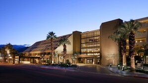 A hotel with a modern design, featuring a large glass facade and palm trees in the foreground. - Hyatt Palm Springs (Palm Springs)