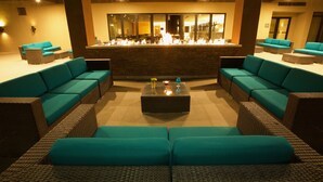 Eine Lounge mit türkisblauen Sofas, einem zentralen Couchtisch und einer Bar mit Kamin.