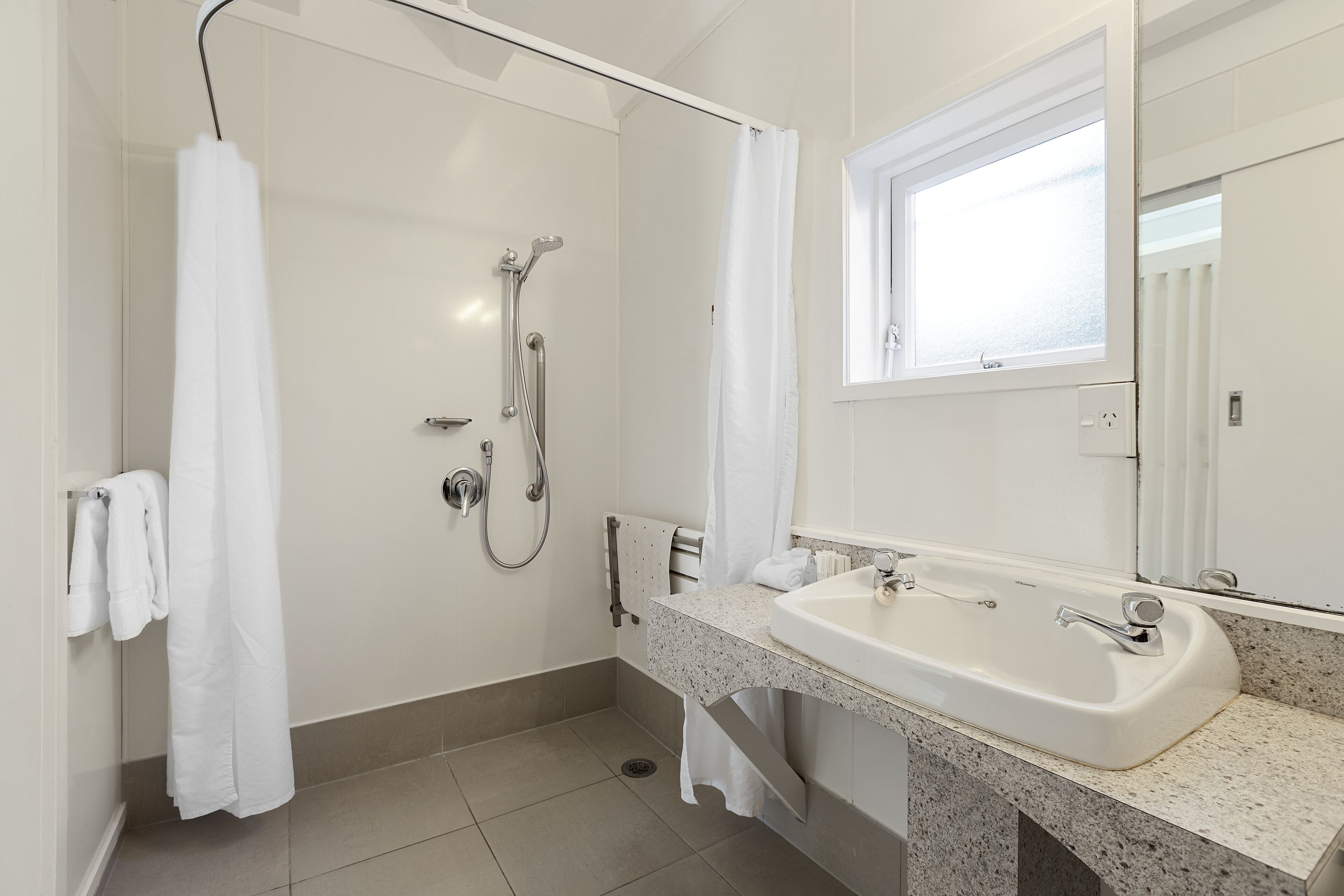A modern bathroom with a shower, a sink, and a large mirror.