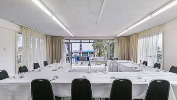 Ein Konferenzraum mit einem langen Tisch, schwarzen Stühlen und Blick auf Gebäude im Freien.