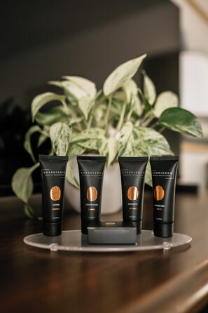 Three black tubes with gold accents on a reflective surface, with a potted plant in the background.