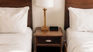 A hotel room with two wooden beds, white linens, a bedside table with a lamp, and a nightstand with a phone and a drawer. - Aurora Inn (Kingston)