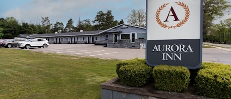 Une enseigne indiquant l’emplacement de l’hôtel Aurora Inn, avec un parking et un bâtiment en arrière-plan.