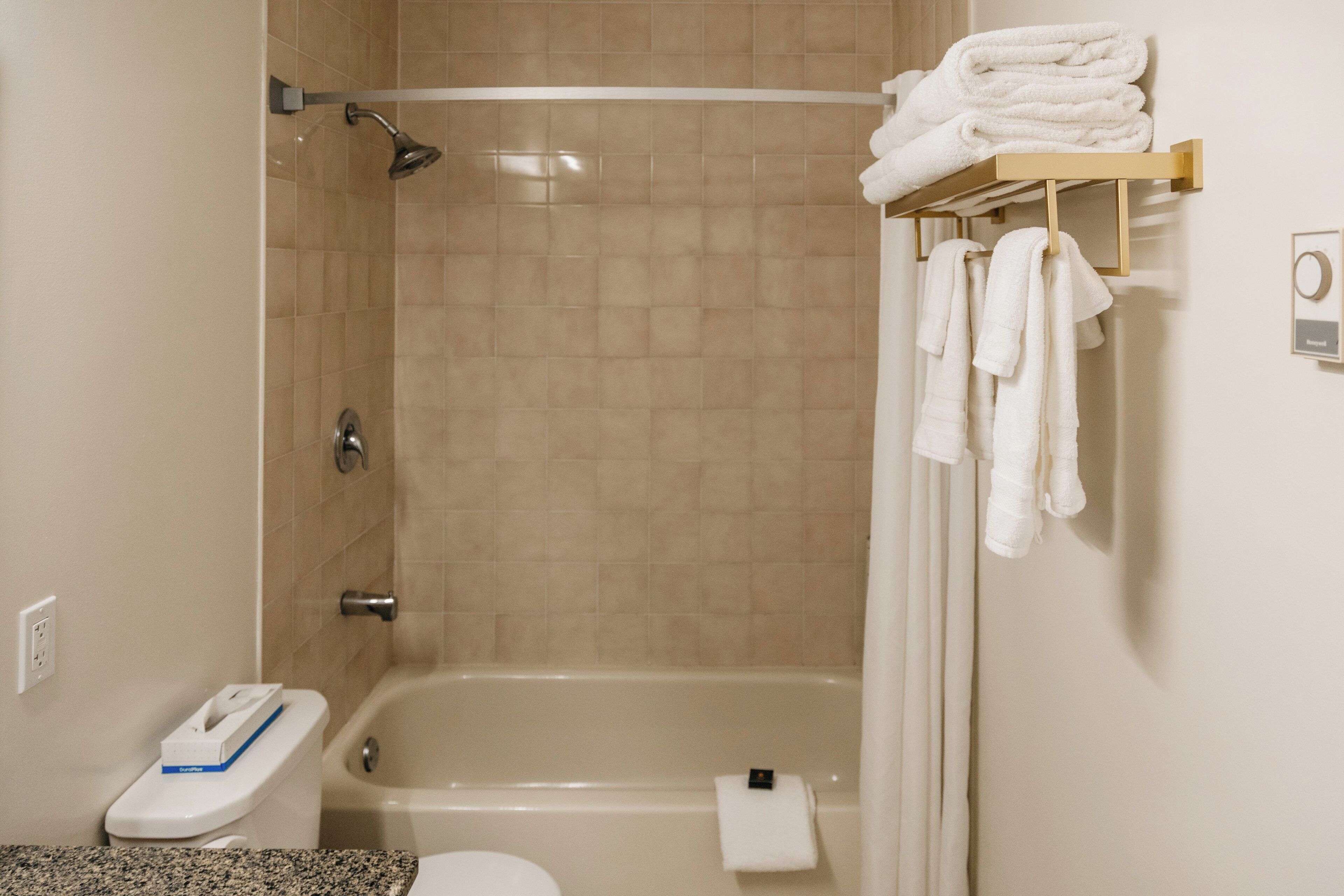 Un baño con ducha, inodoro y un perchero con toallas.
