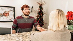 A reception area with a marble counter, a framed picture on the wall, and a Christmas tree.