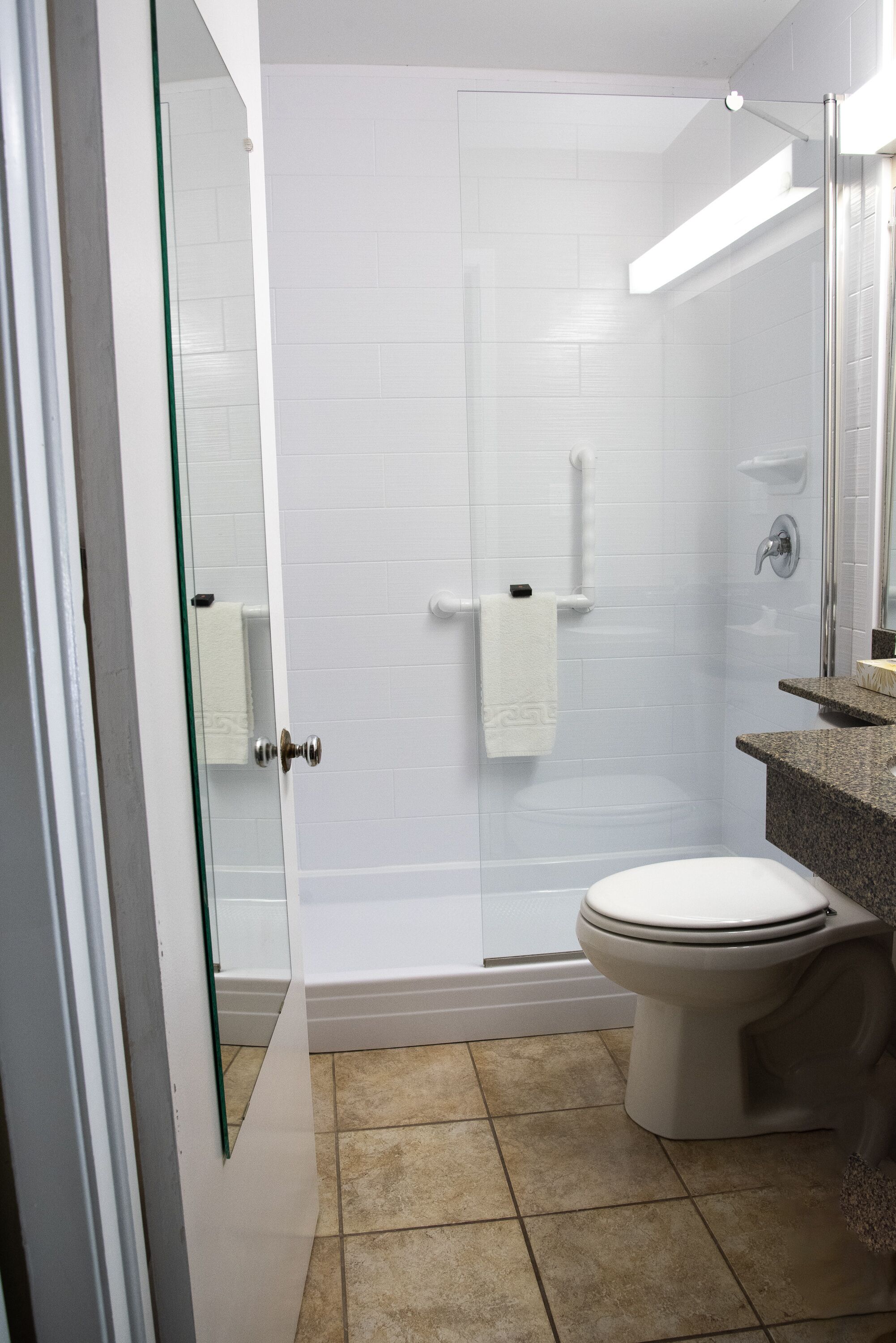 Une salle de bain dotée d’une douche à parois de verre, de toilettes et d’un lavabo avec un plan de travail en granit.