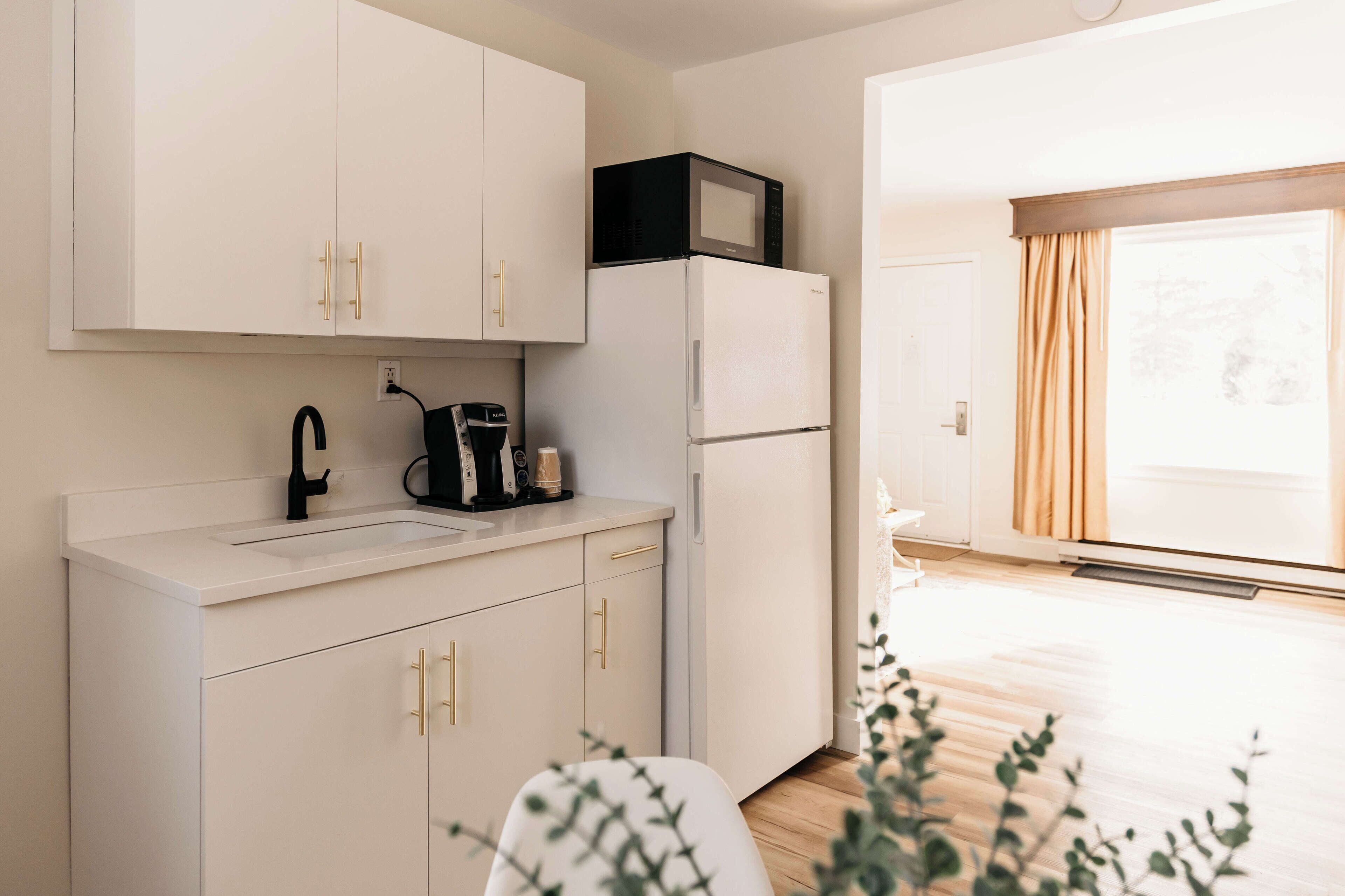 A modern kitchen with white cabinets, a black microwave, and a refrigerator.