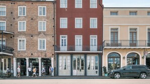 A row of three-story buildings with large windows and a ground-level entrance. - French Market Inn (New Orleans)