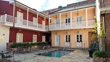 A courtyard with a swimming pool, outdoor seating, and a two-story building with balconies.