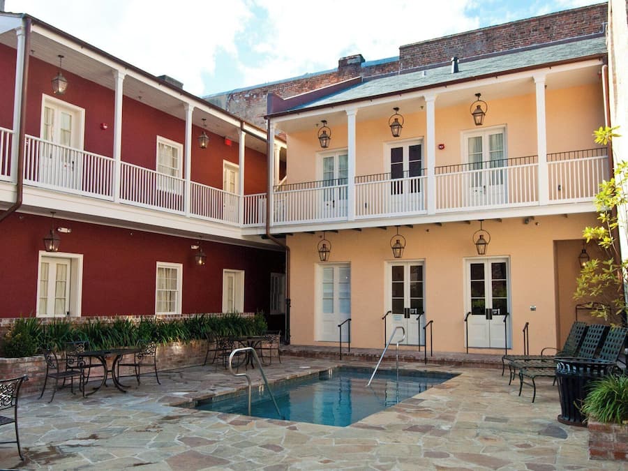 Une cour avec une piscine, un espace salon extérieur et un bâtiment à deux étages doté de balcons.