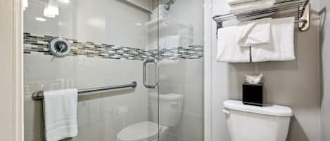 A modern bathroom with a glass shower enclosure, a glass door, a toilet, and a towel rack with folded towels.