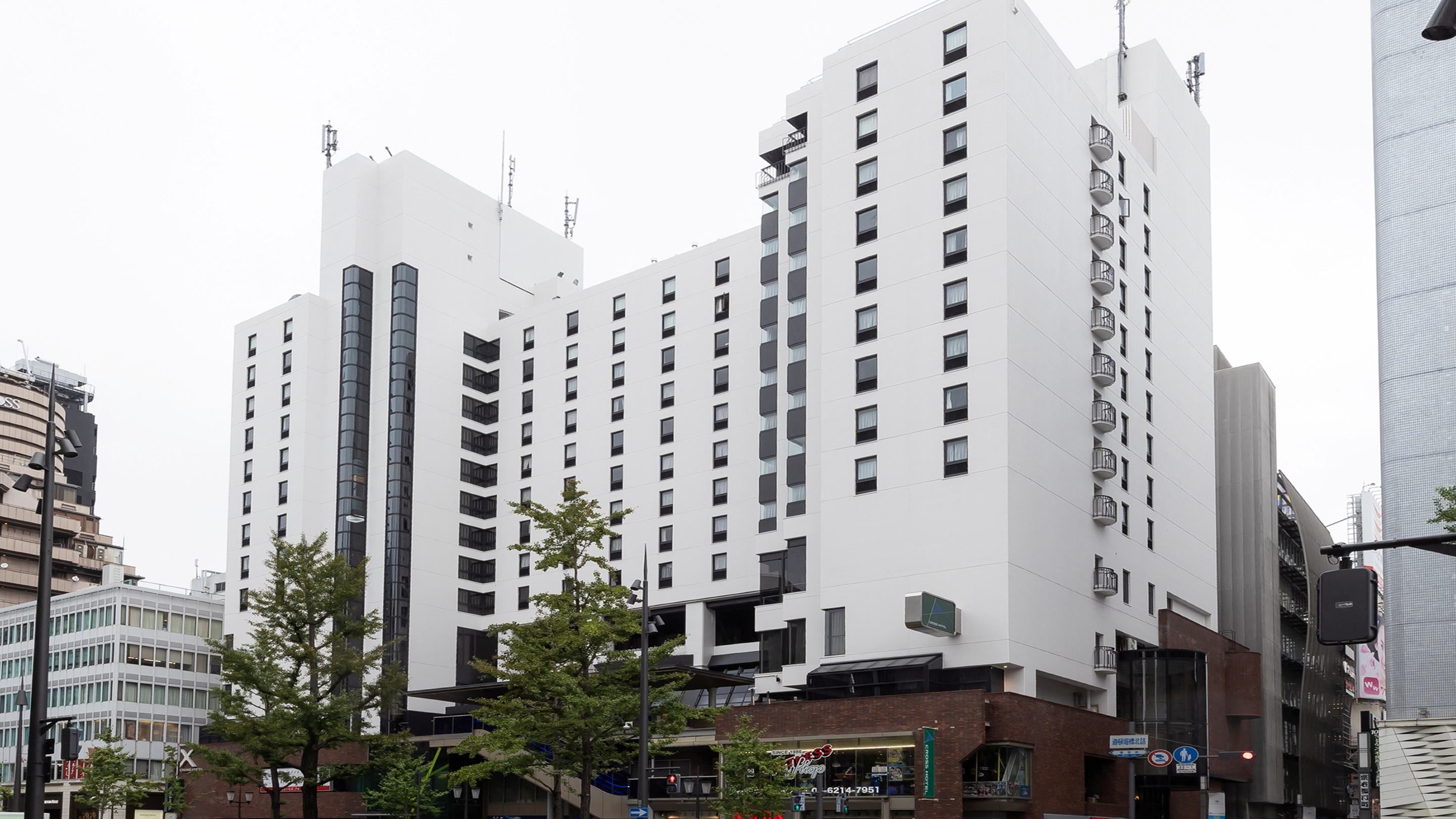Un hotel de varios pisos con un diseño moderno, que cuenta con una entrada destacada con fachada de vidrio y un letrero de restaurante visible.
