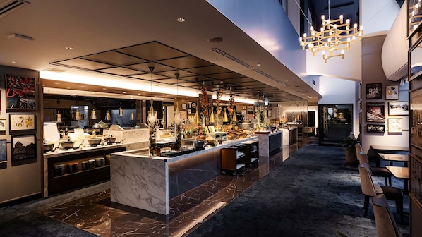 A modern hotel lobby with a marble reception desk, pendant lighting, and a high ceiling.