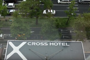 Un edificio grande con un llamativo letrero en forma de 'X' y la inscripción 'CROSS HOTEL' en su fachada.