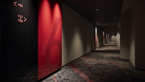 A modern hotel corridor with a red accent wall, directional arrows, and a carpeted floor. - Cross Hotel Osaka(ORIX HOTELS & RESORTS) (Osaka)