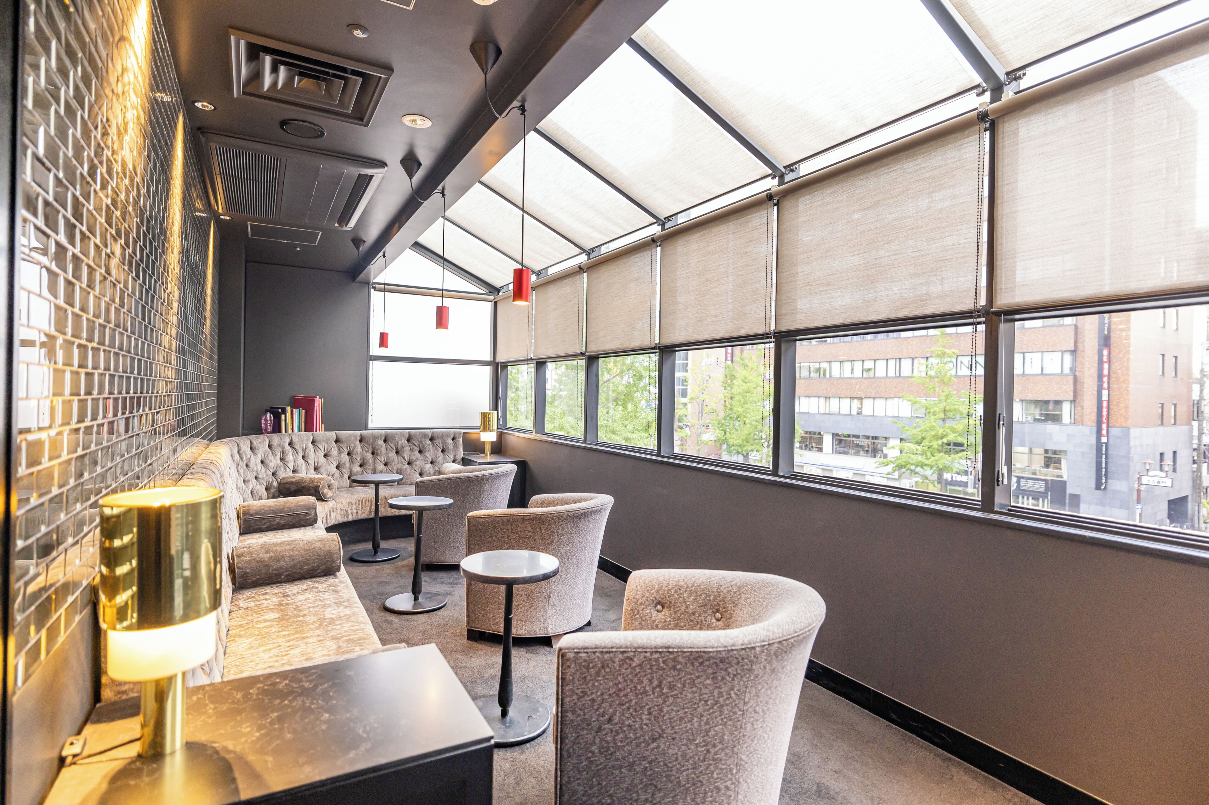 A modern interior with a seating area, tables, and a view through large windows.