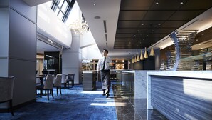 A modern hotel lobby with a marble reception desk, a seating area with chairs, and a high ceiling with natural light. - Cross Hotel Osaka(ORIX HOTELS & RESORTS) (Osaka)