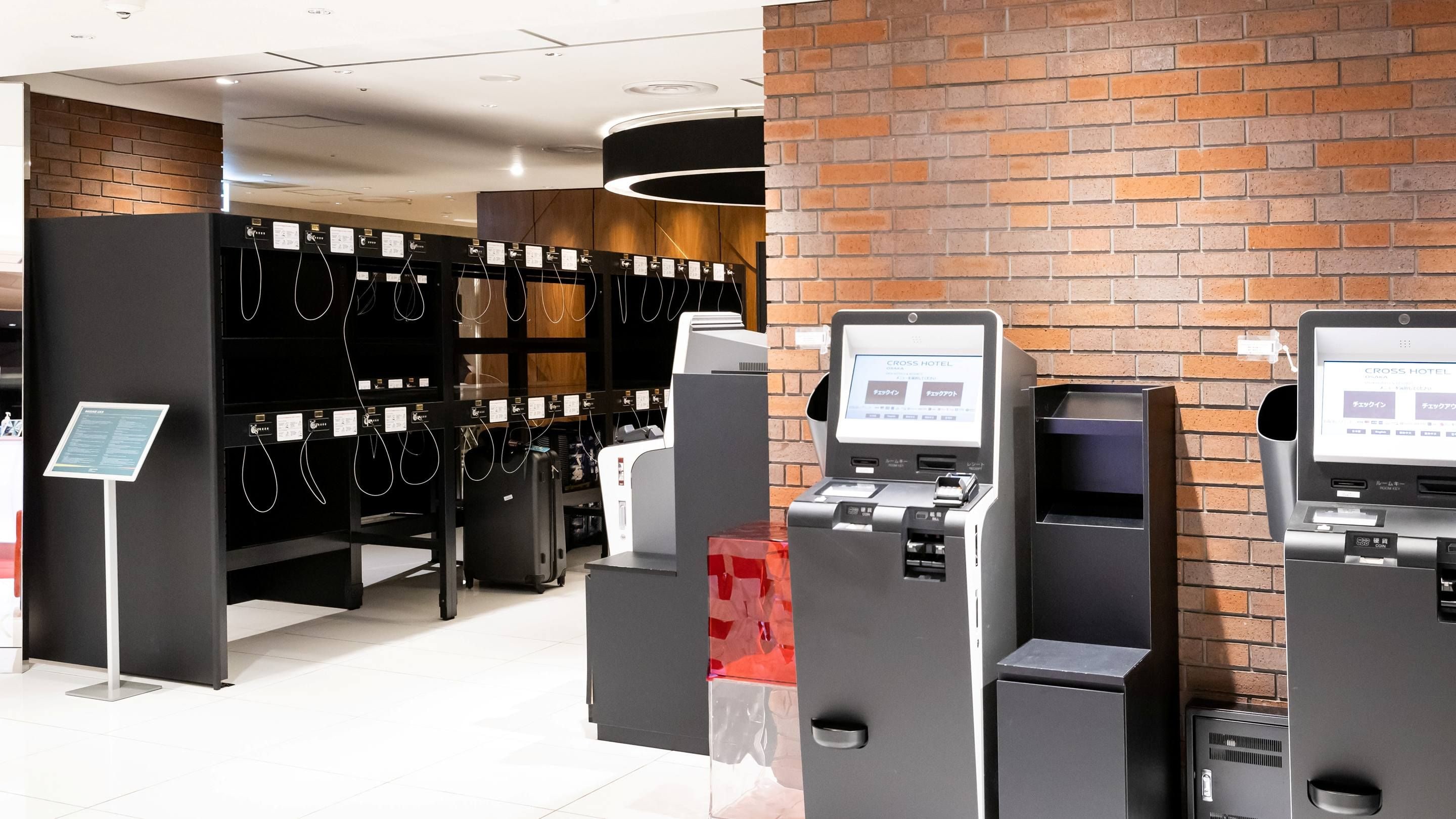 A hotel reception area with self-service kiosks and a brick wall.