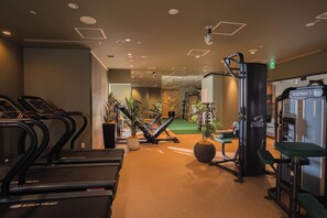 Un gimnasio con cintas de correr, máquinas de pesas y colchonetas de ejercicio.