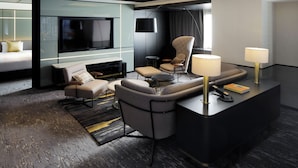 A modern hotel room with a sectional sofa, a flat-screen TV, a desk with a lamp, and a bed with a headboard. - Cross Hotel Osaka(ORIX HOTELS & RESORTS) (Osaka)