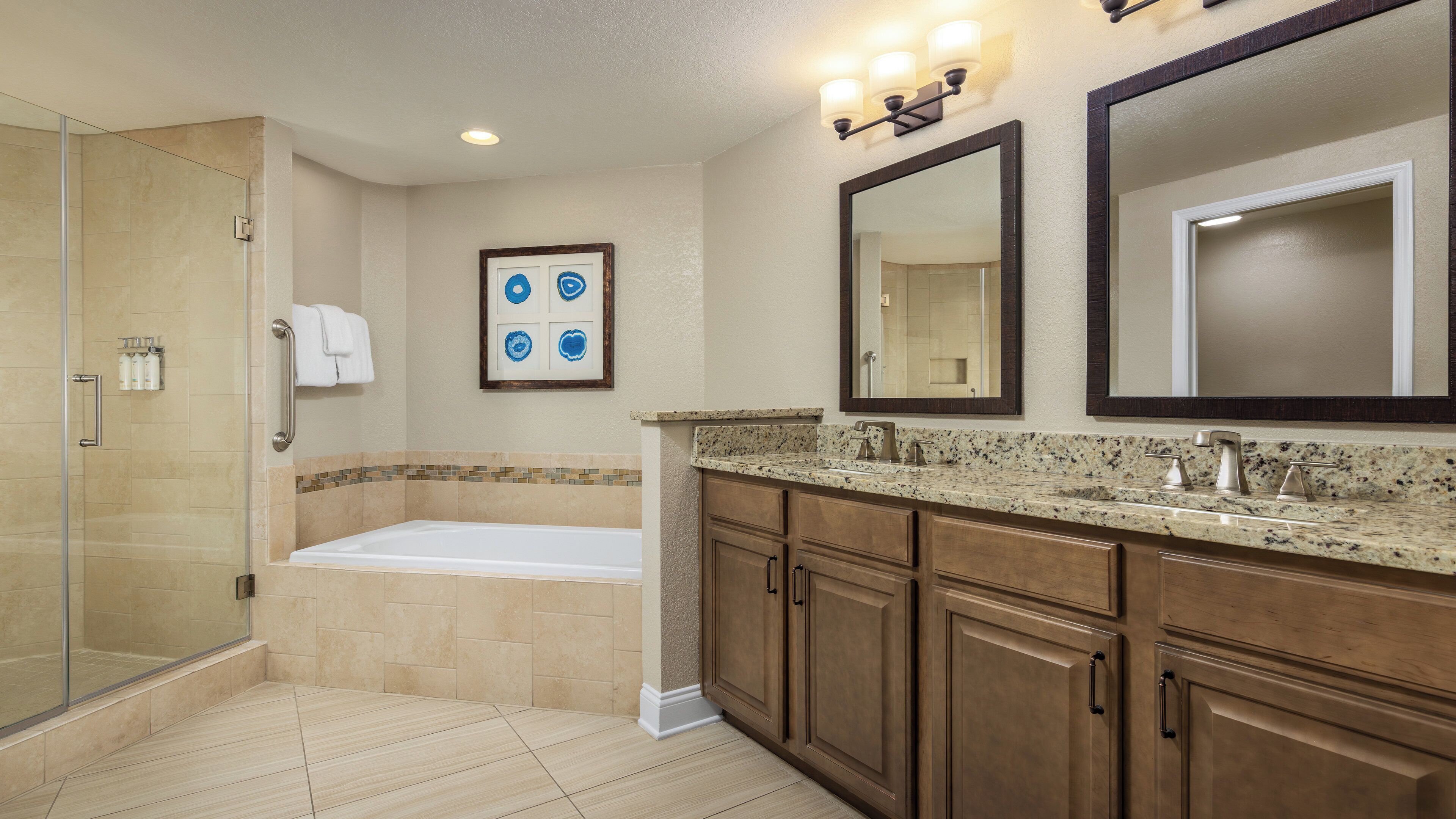 A modern bathroom with a walk-in shower, a bathtub, and a vanity with a large mirror.