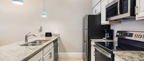 A modern kitchen with granite countertops, stainless steel appliances, and white cabinetry.