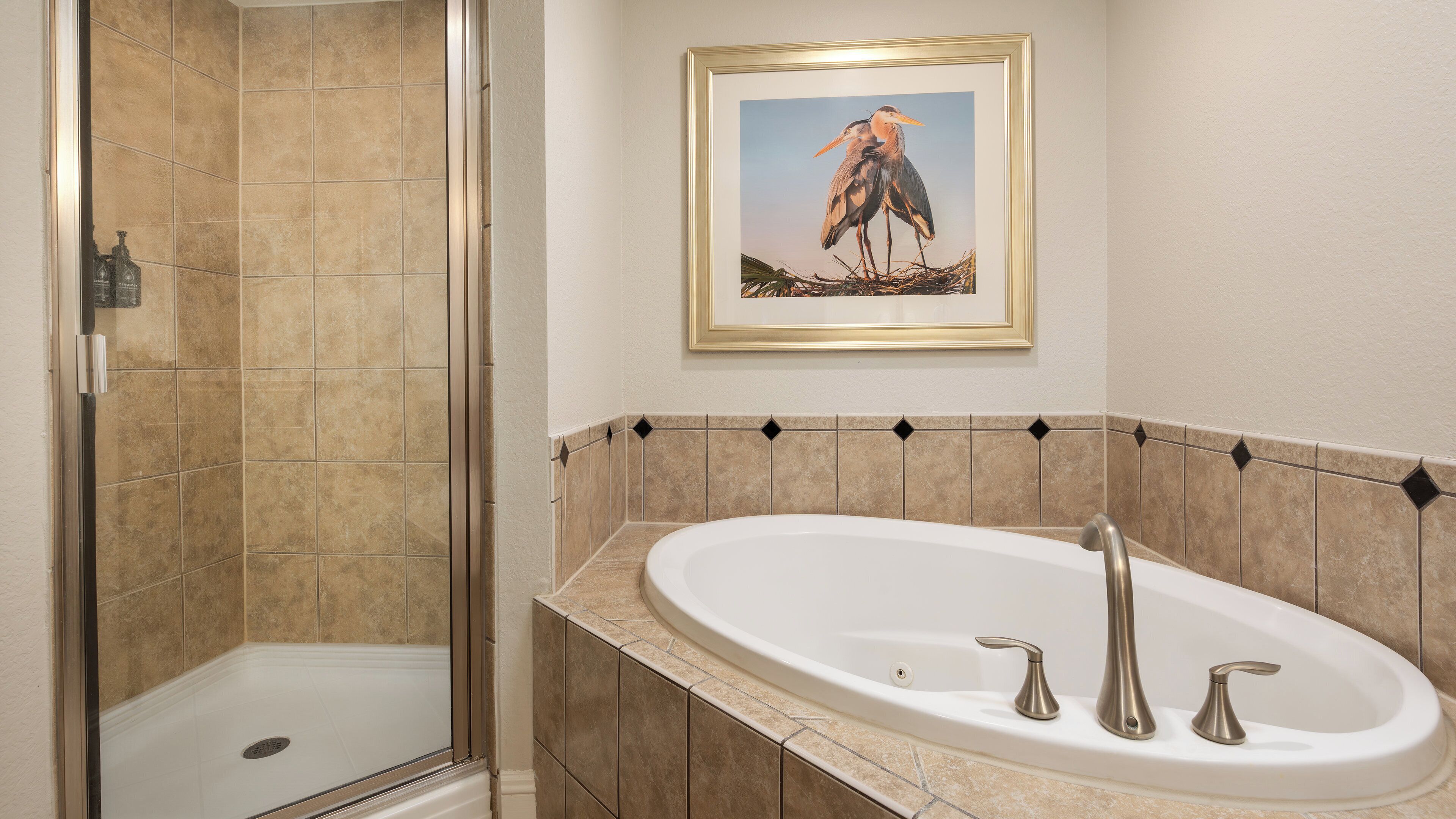 A bathroom with a shower, a bathtub, and a framed picture on the wall.
