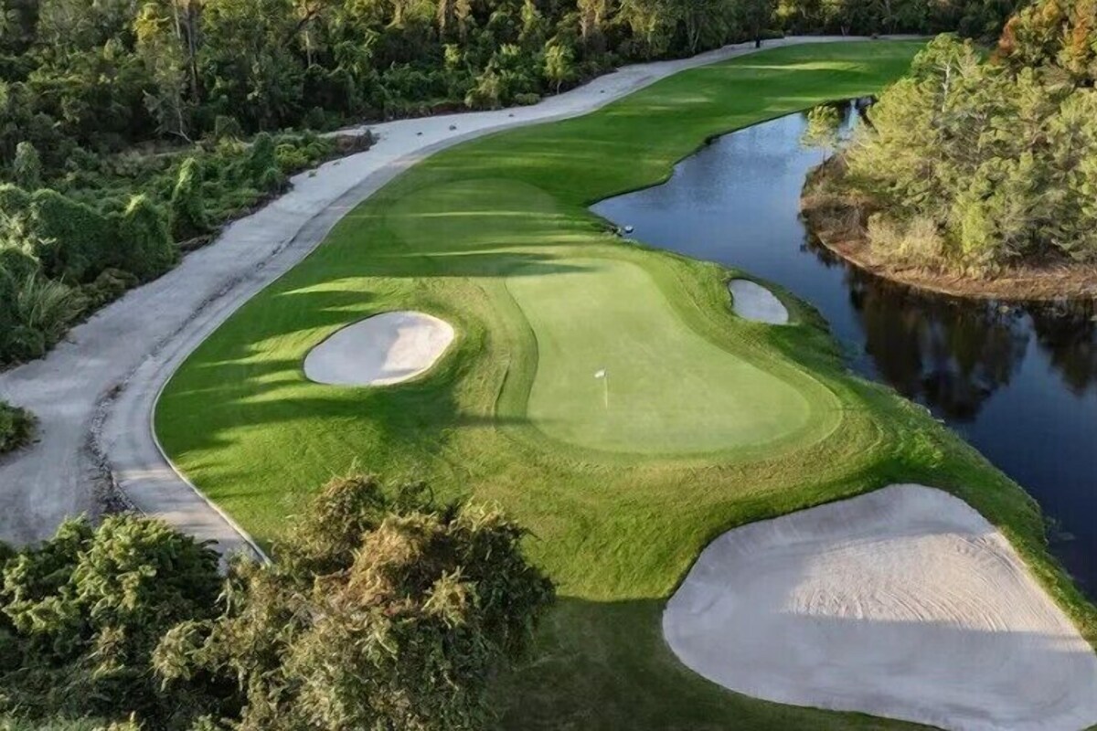 A golf course with a water hazard, sand bunkers, and a flagstick.